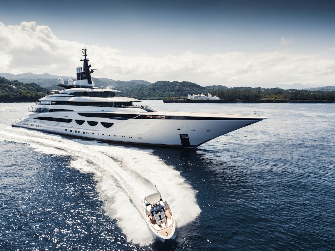 Large Yacht Cruising Deep Blue Waters with a Small Boat Speeding By