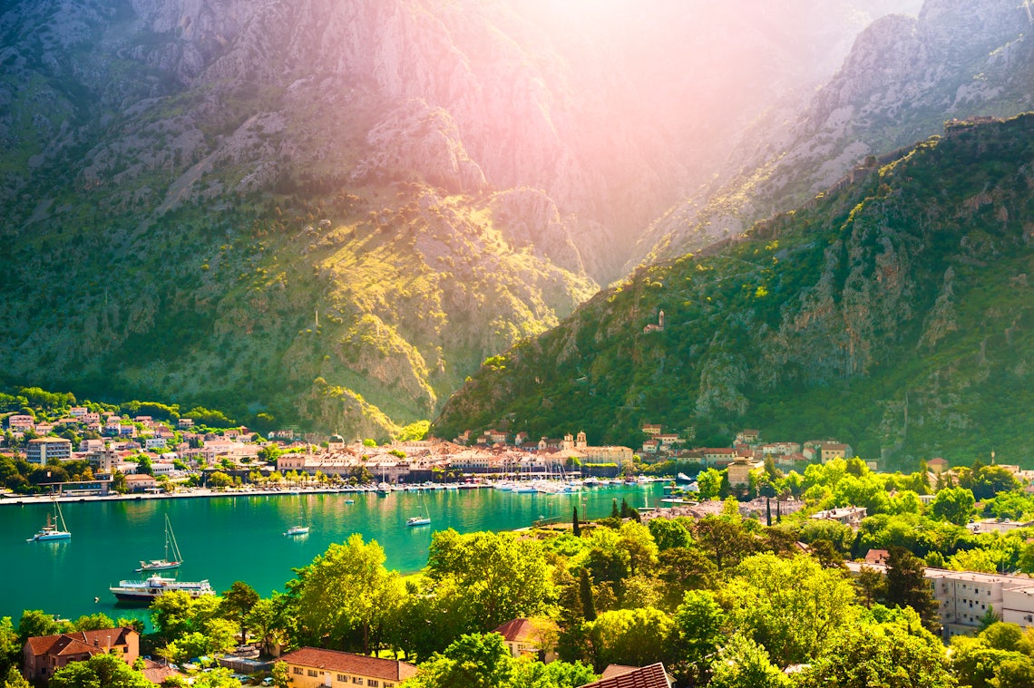 Sea in Montenegro with a town boardering it and huge mountains in the background